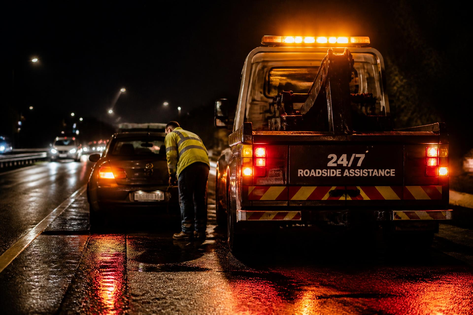 Roadside assistance truck helping a stranded car on a Memphis highway at night